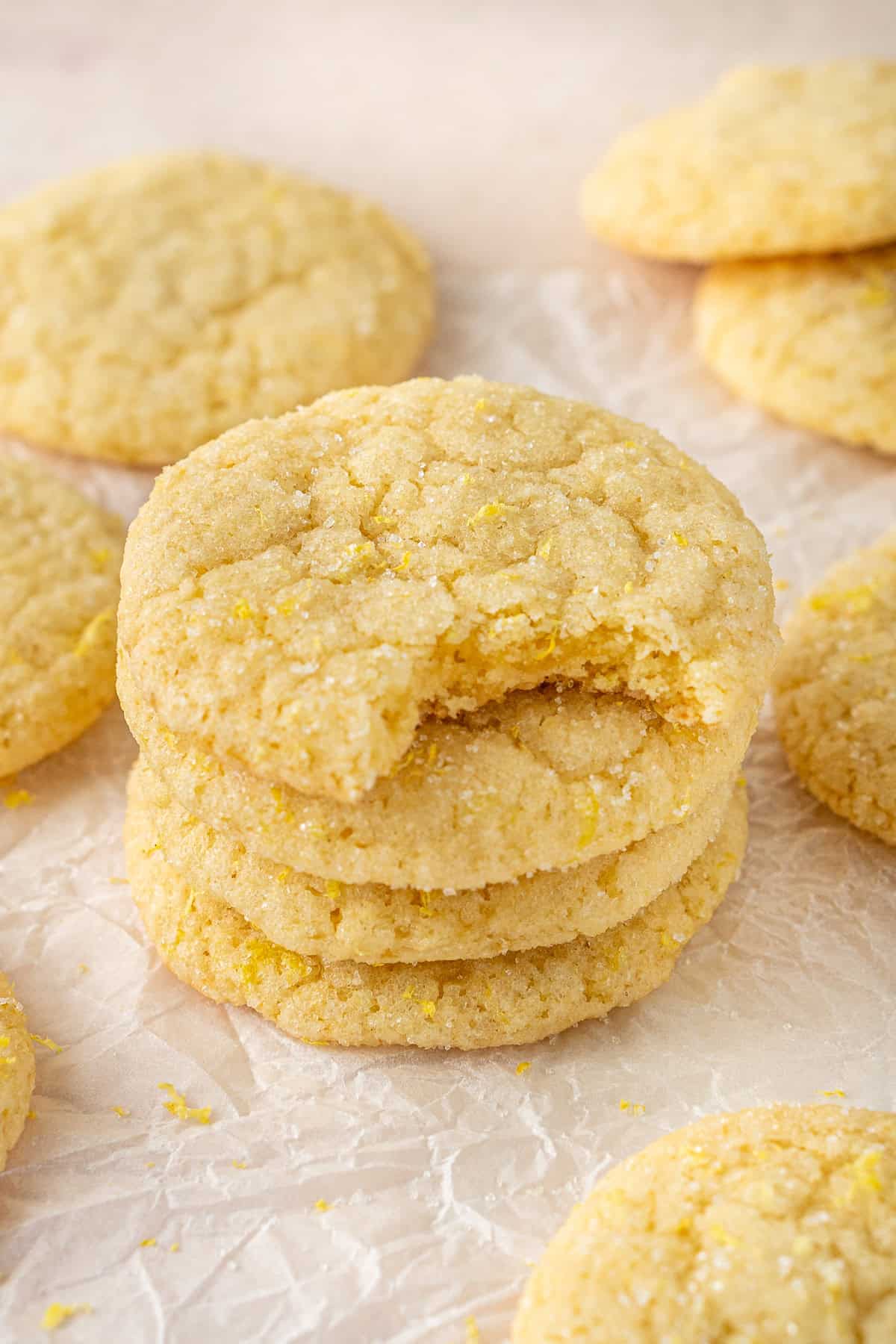 A stack of lemon sugar cookies, one with a bite taken.