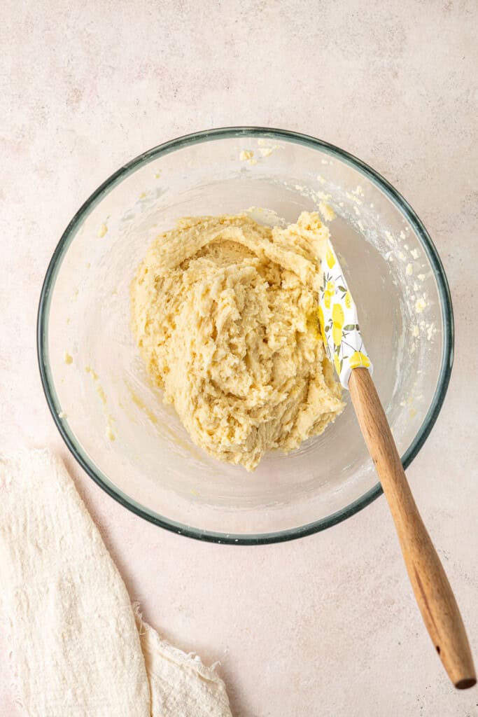 The soft cookie dough in a mixing bowl with a spatula. 