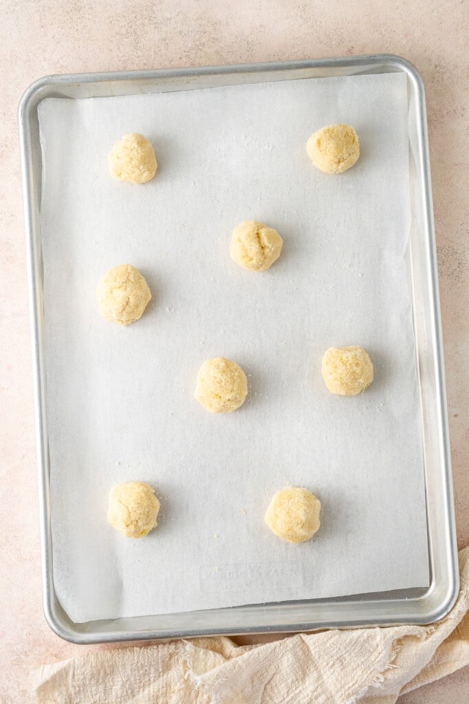 Balls of soft cookie dough on a baking tray.