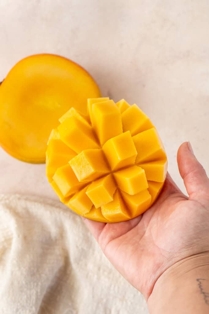 A hand holding a cut mango.