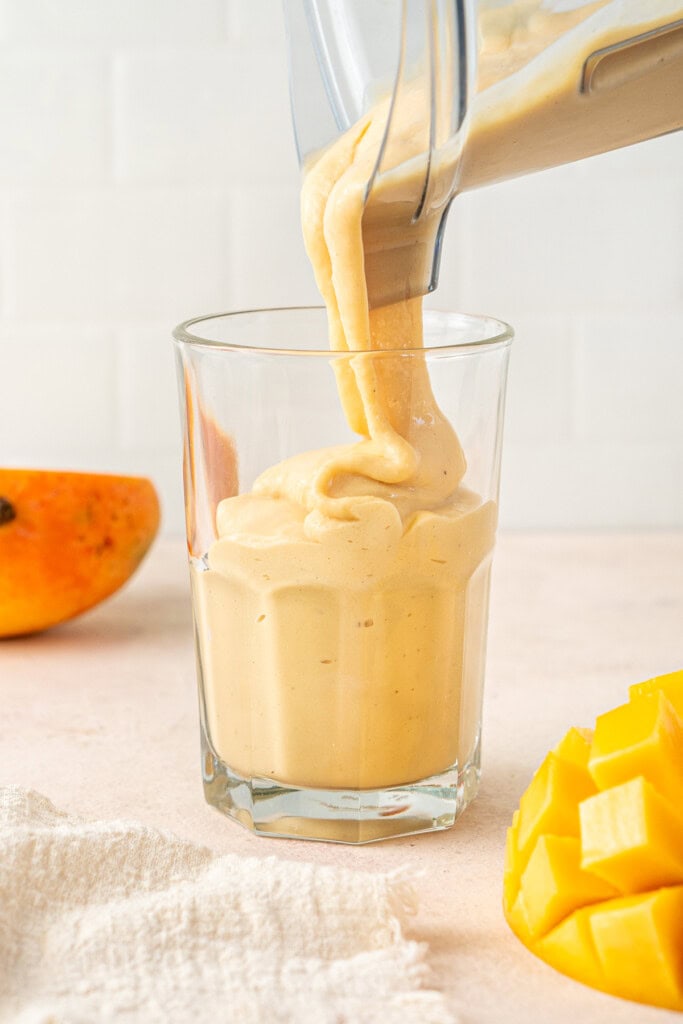 The thick smoothie being poured into a glass.