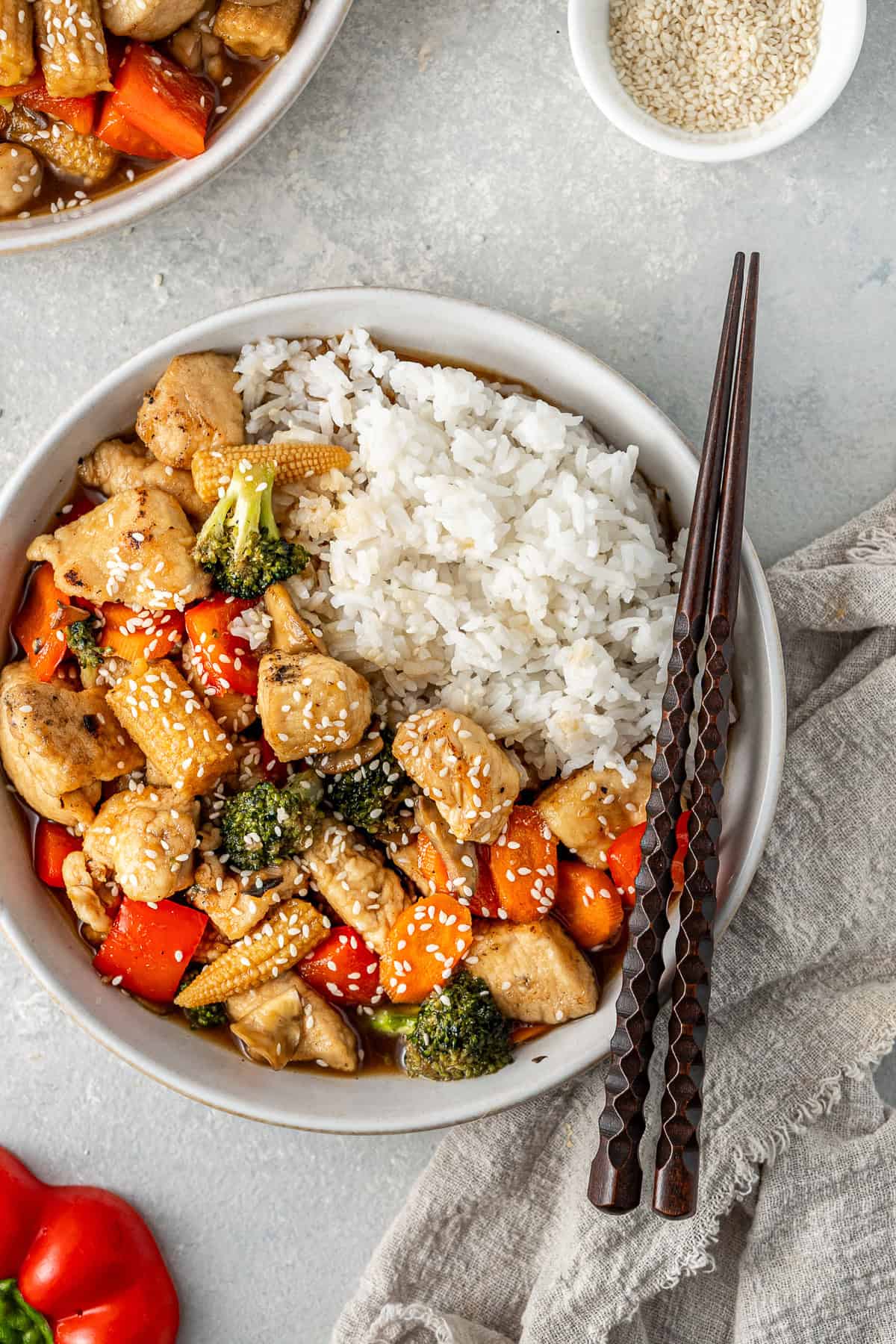 Close up of honey garlic chicken stir fry served in a bowl with rice and chopsticks.