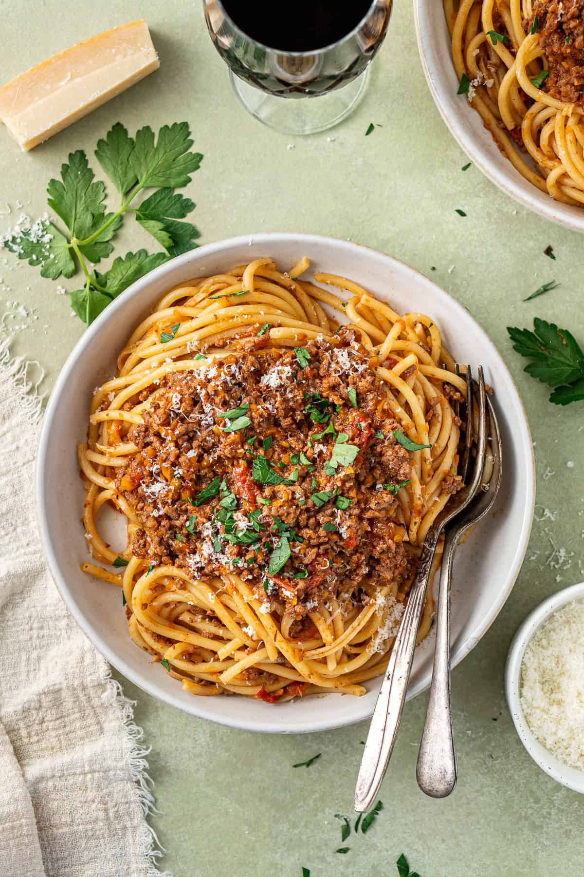 Slow cooker bolognese served in bowls with spaghetti topped with fresh parsley. 