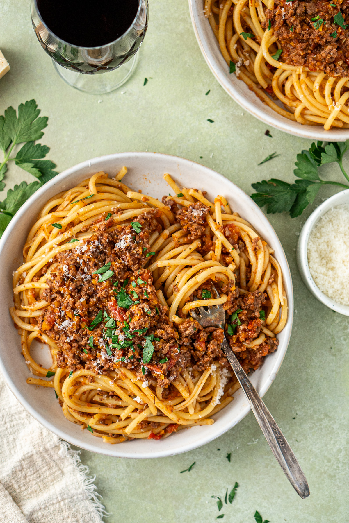 The bolognese served over pasta in bowls with a fork.