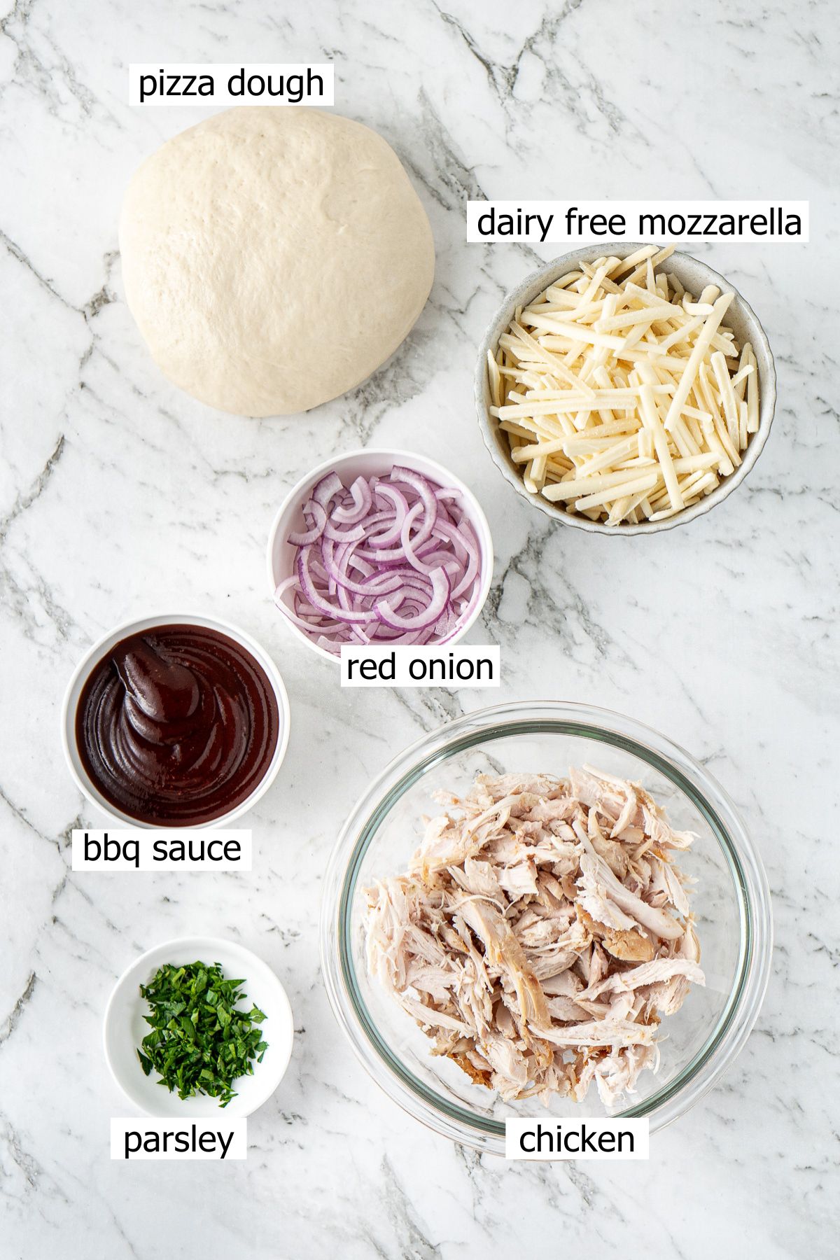 All ingredients needed to make dairy free BBQ chicken pizza laid out in bowls.