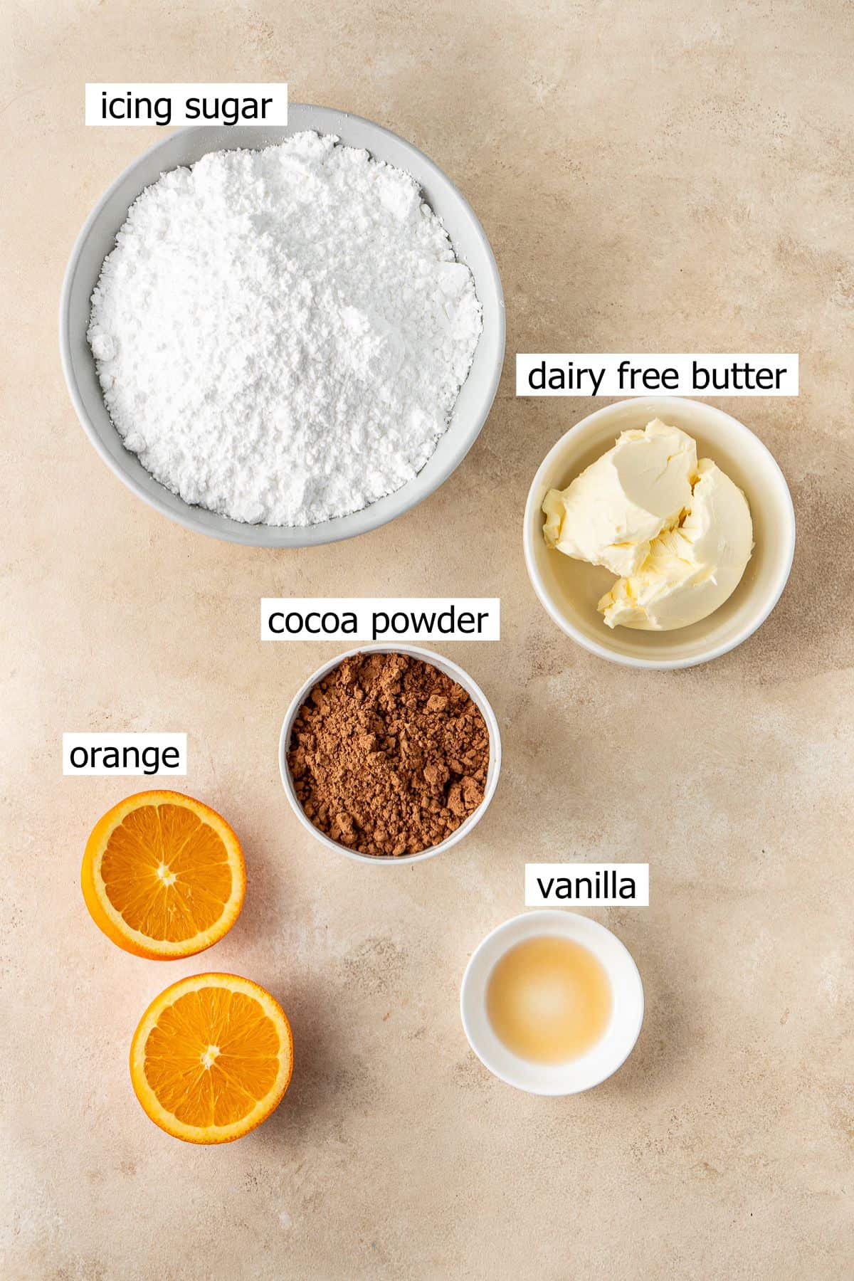 All ingredients needed to make chocolate orange buttercream laid out in small bowls.