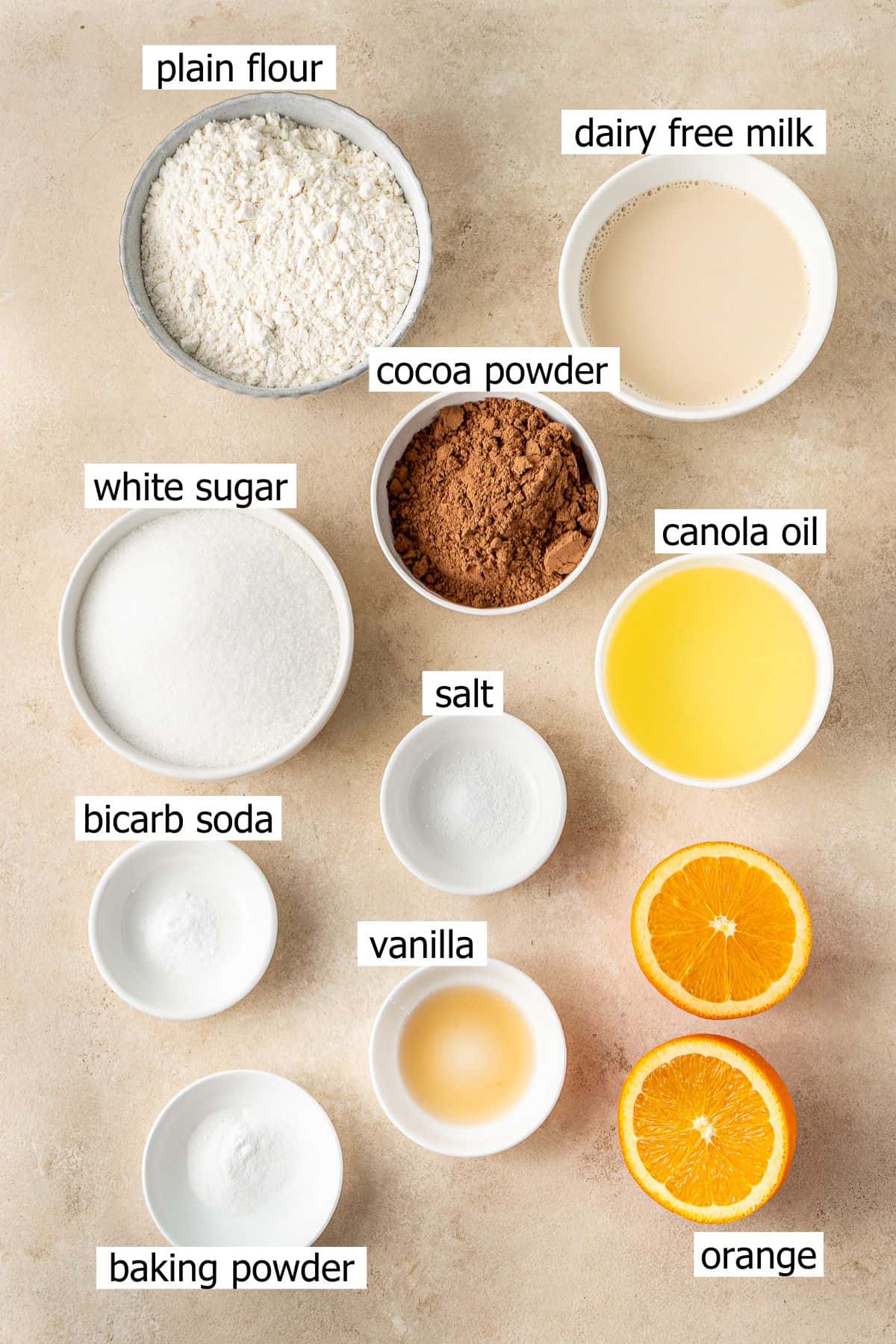 All ingredients needed to make chocolate orange cupcakes laid out in small bowls.