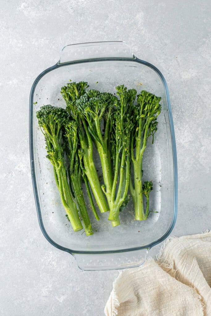 Tossing the broccolini in a shallow dish.