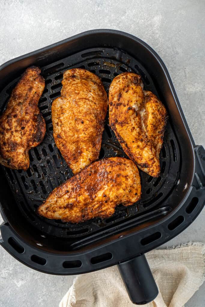 Cooked chicken breasts in the air fryer basket.