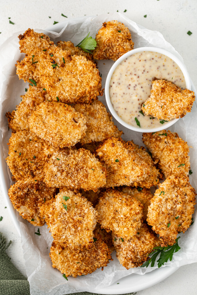 Air fried chicken nuggets on a plate with honey mustard sauce.