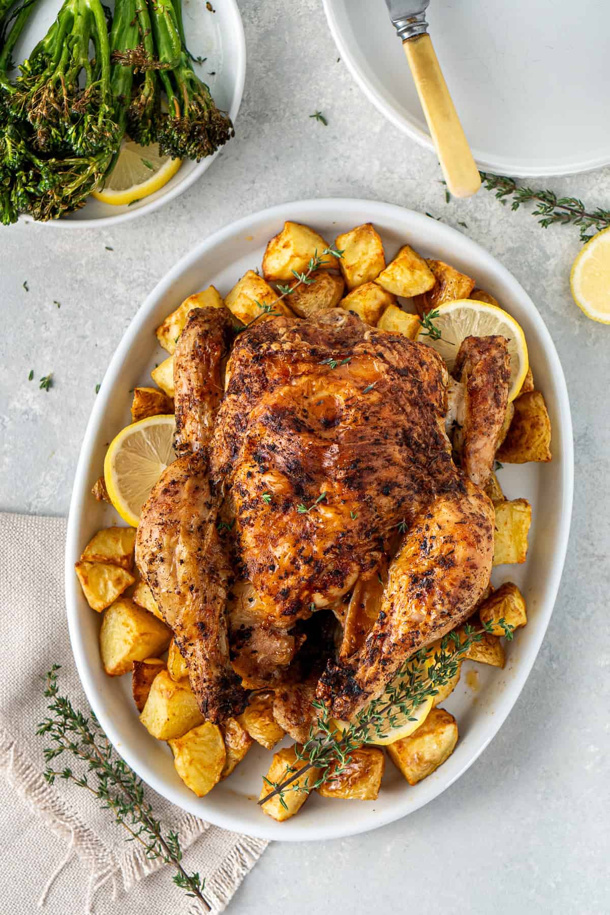 The whole air fryer roast chicken on a plate with potatoes. 