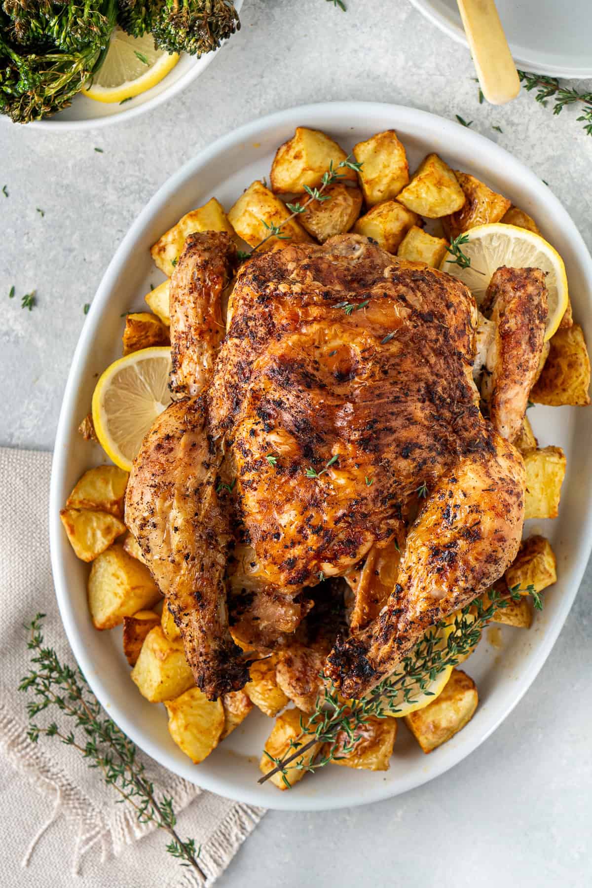 Whole roasted chicken on a plate with potatoes.