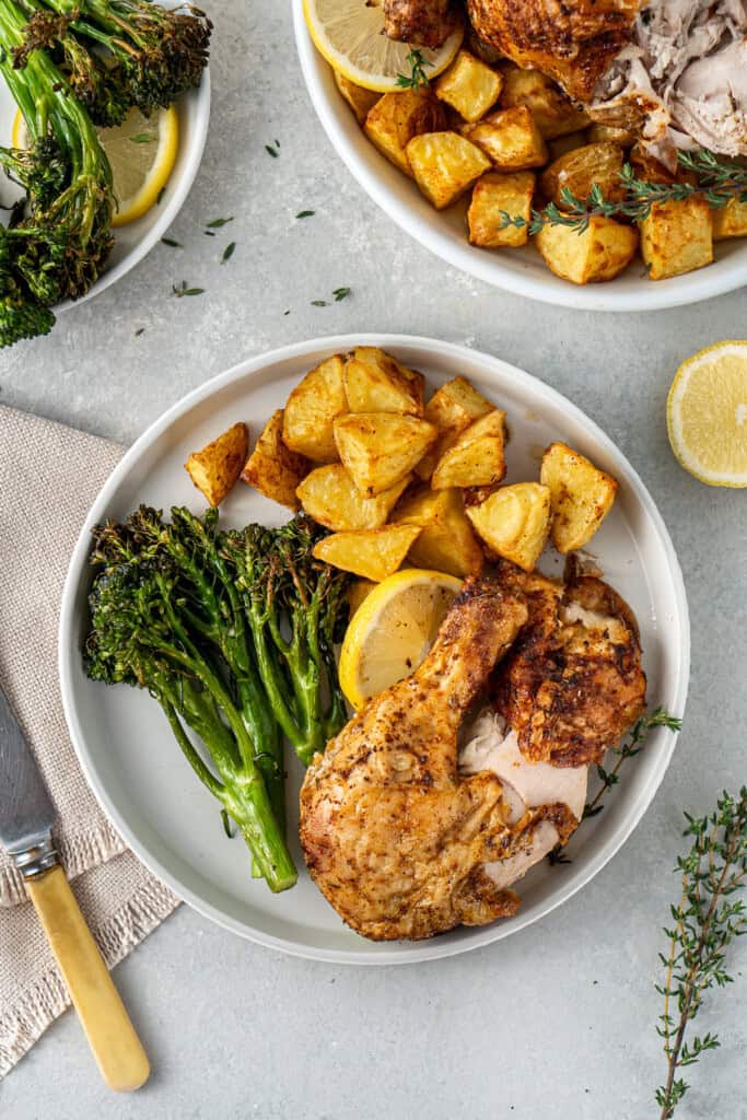 Air fryer roast chicken and potatoes with broccolini on a plate.