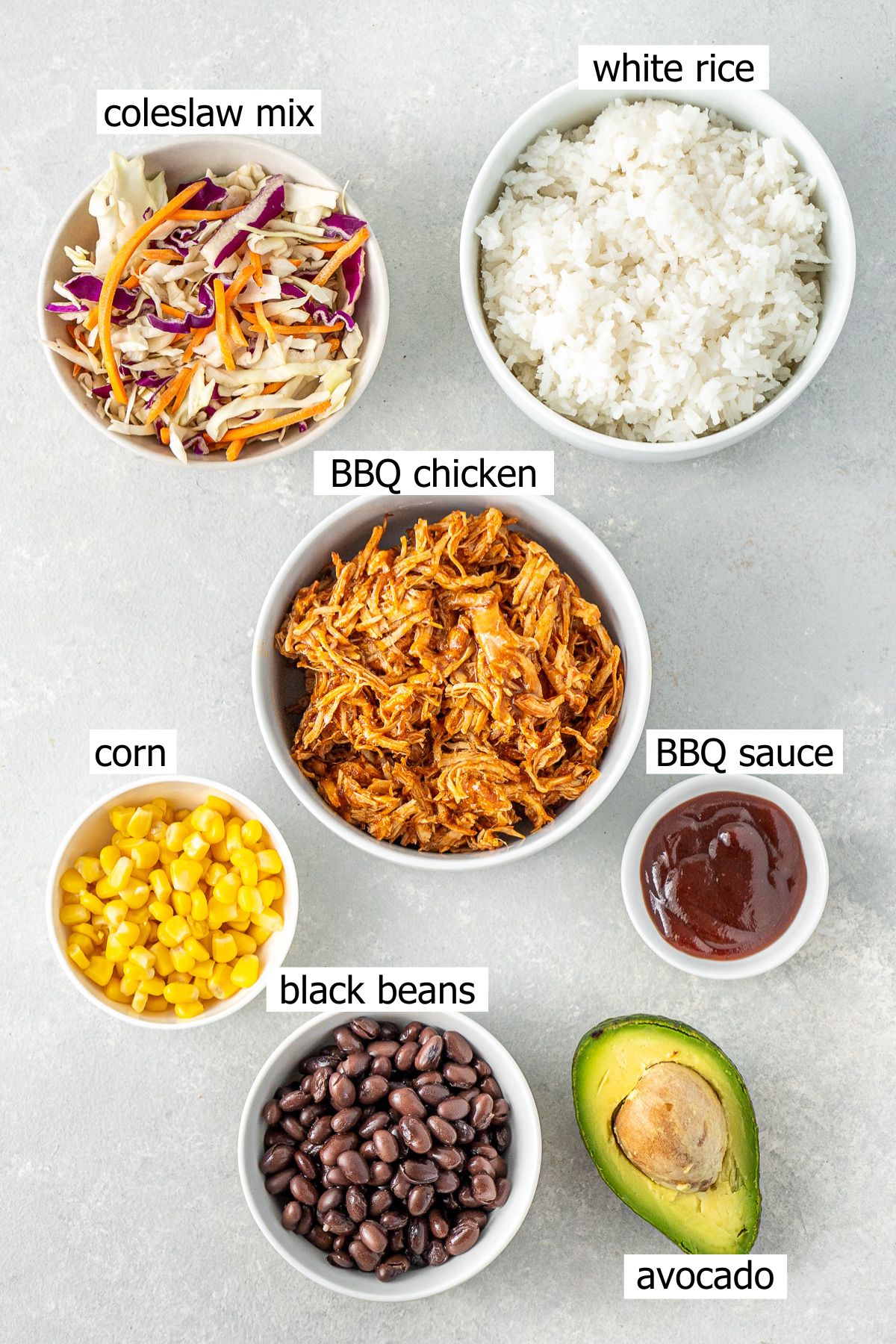 All ingredients needed to make BBQ chicken bowls laid out in small bowls.