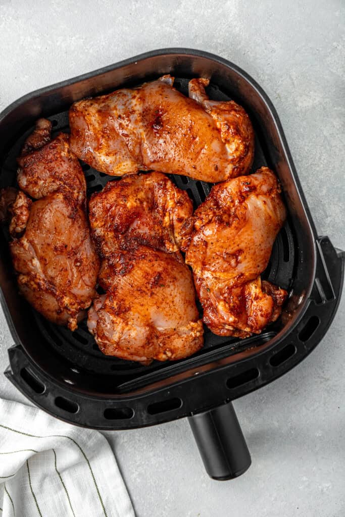 Seasoned chicken in the air fryer basket.