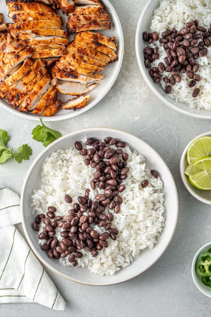 Assembling the bowls with rice and beans and sliced chicken thighs.