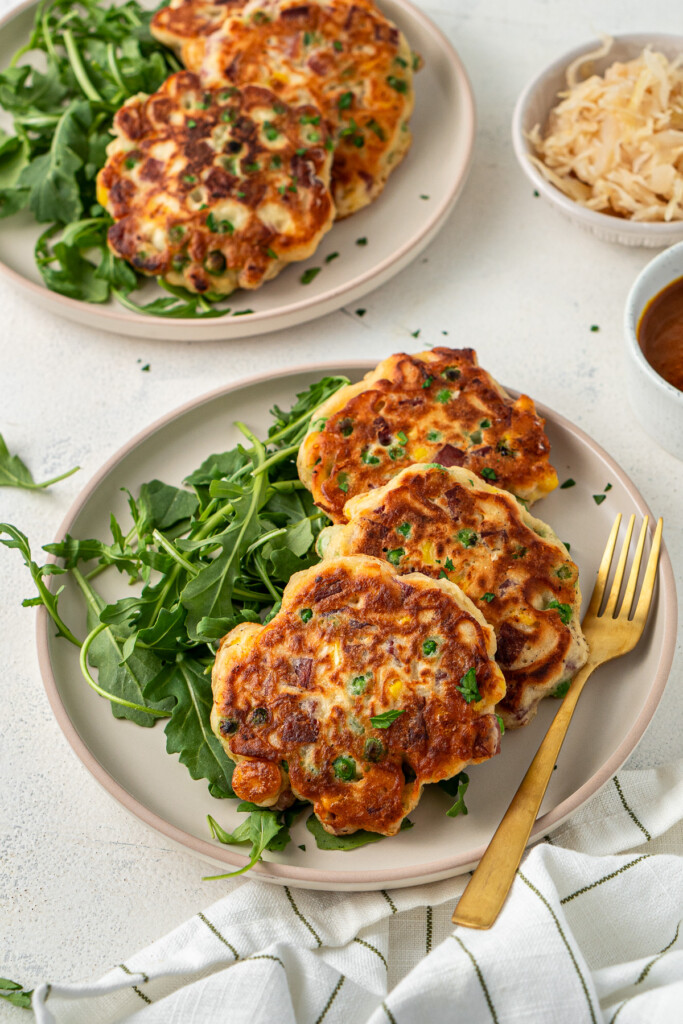 Fritters served on a plate with salad and sauerkraut. 