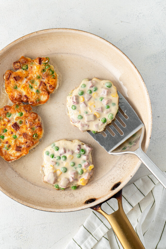 Flipping the fritters in a pan.