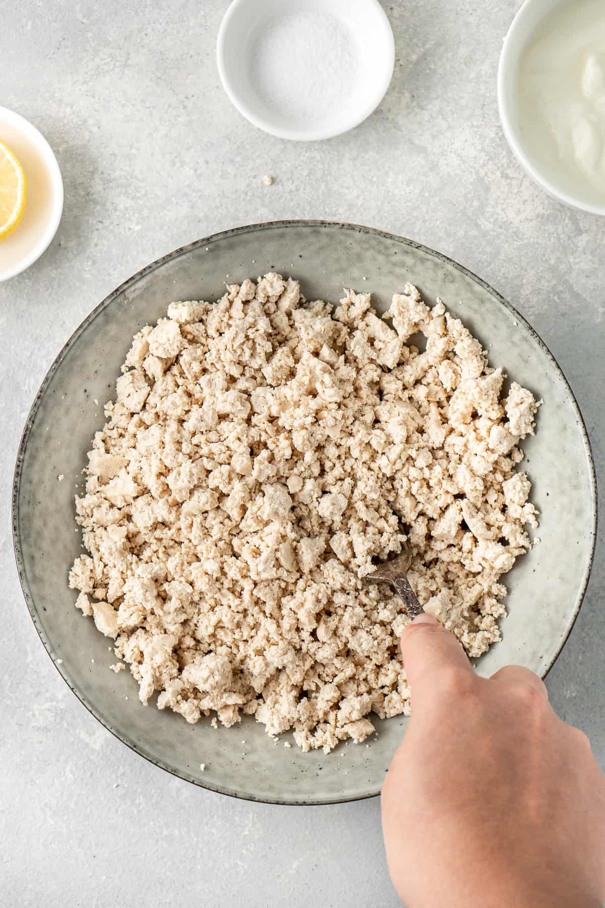 Mashing the tofu to resembled curds.