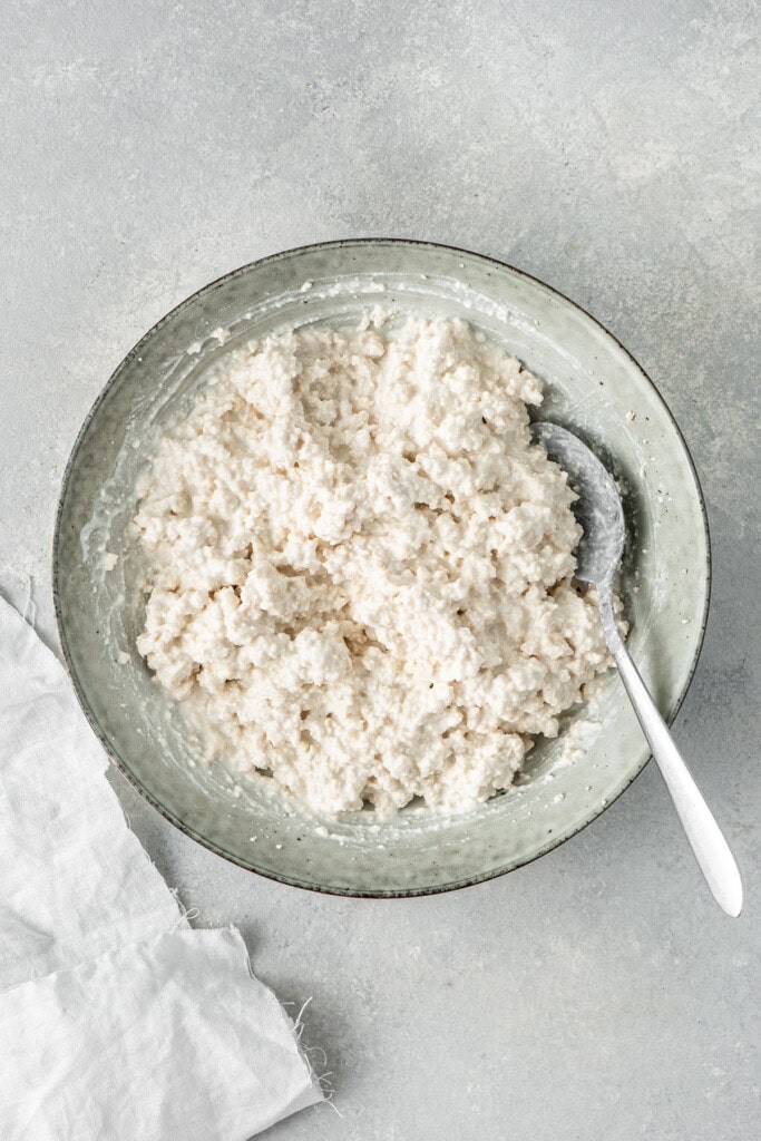 Dairy free cottage cheese mixed in a bowl with a spoon.