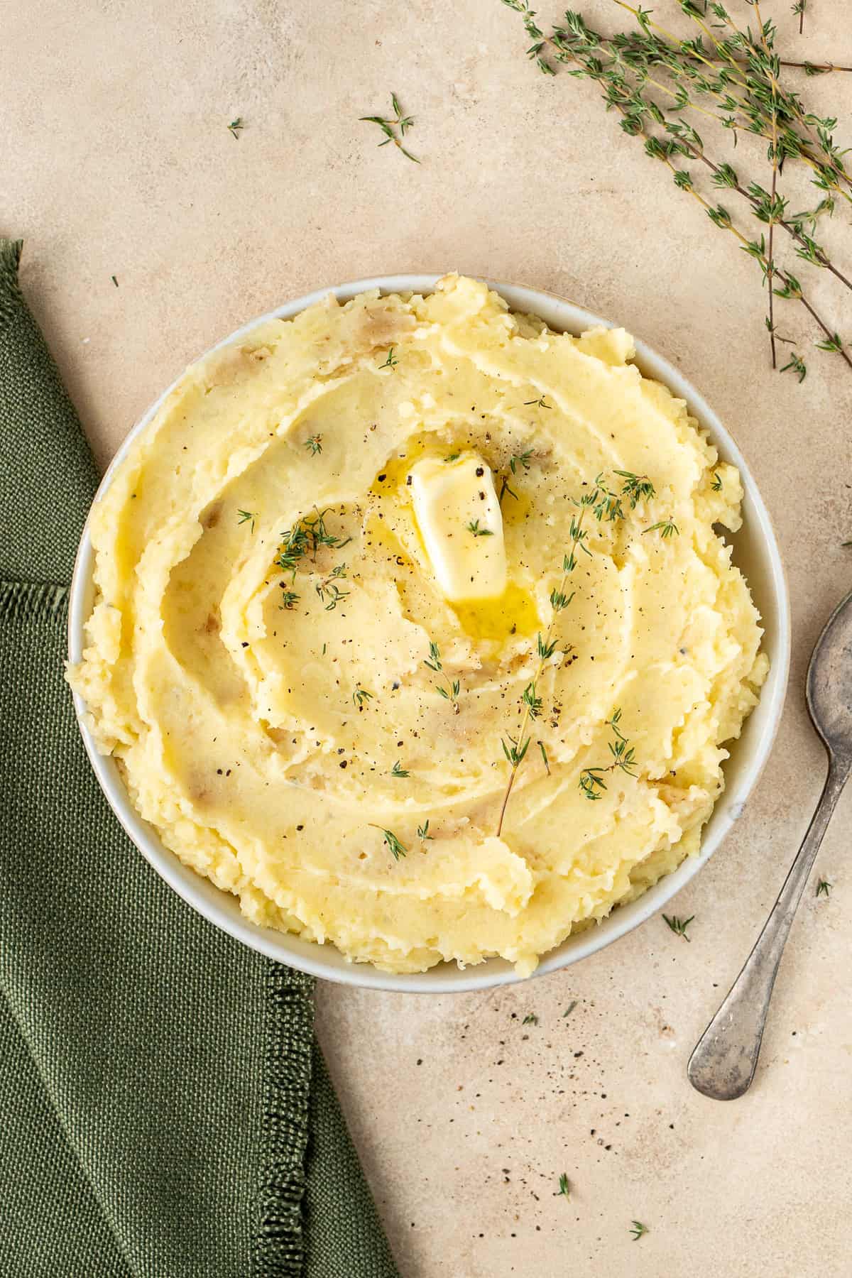 Mashed potatoes in a bowl with dairy free butter and thyme.