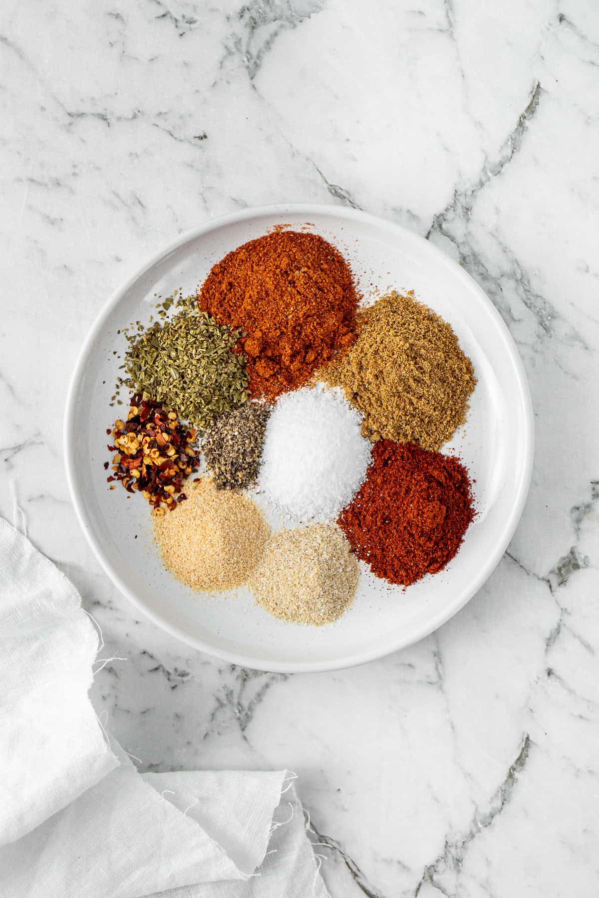 All the spices needed to make homemade taco seasoning laid out on a plate.