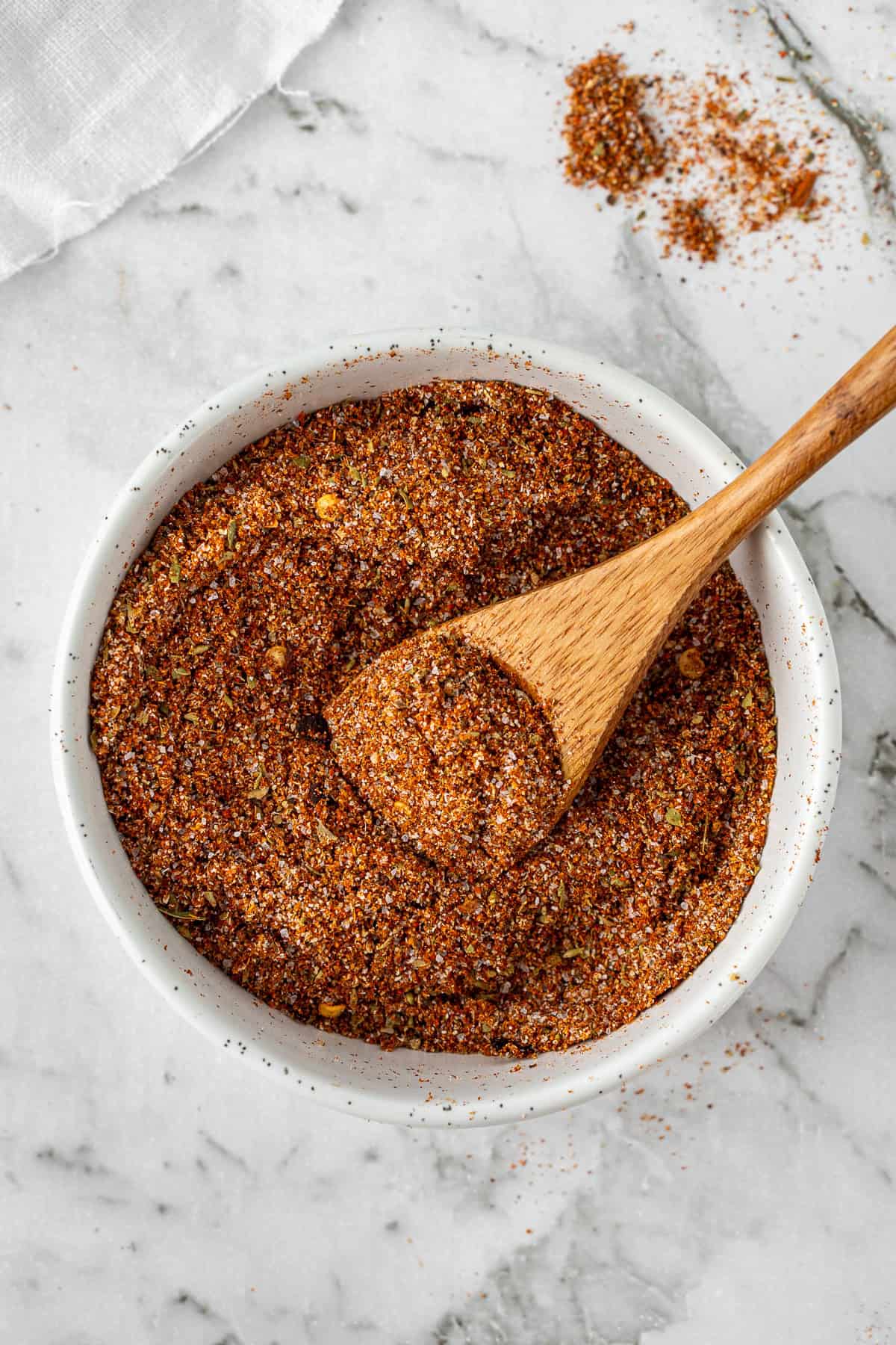 The mixed homemade taco seasoning in a bowl with a small wooden spoon.