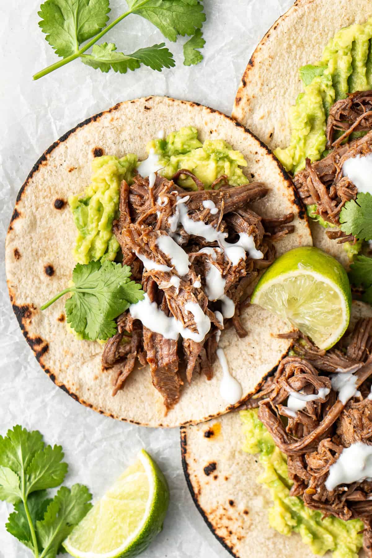 The shredded beef tacos with avocados laid flat. 
