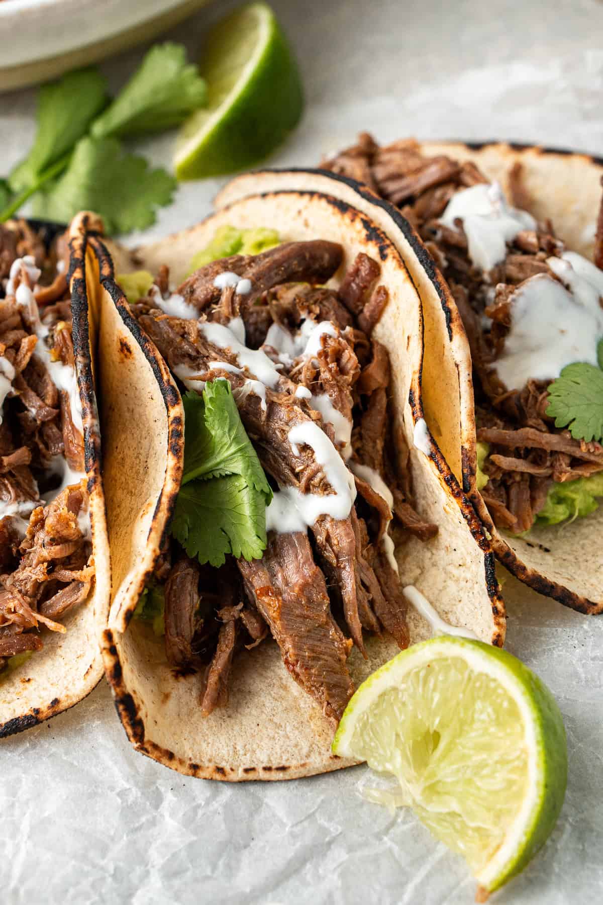 Close up of shredded beef tacos with lime.