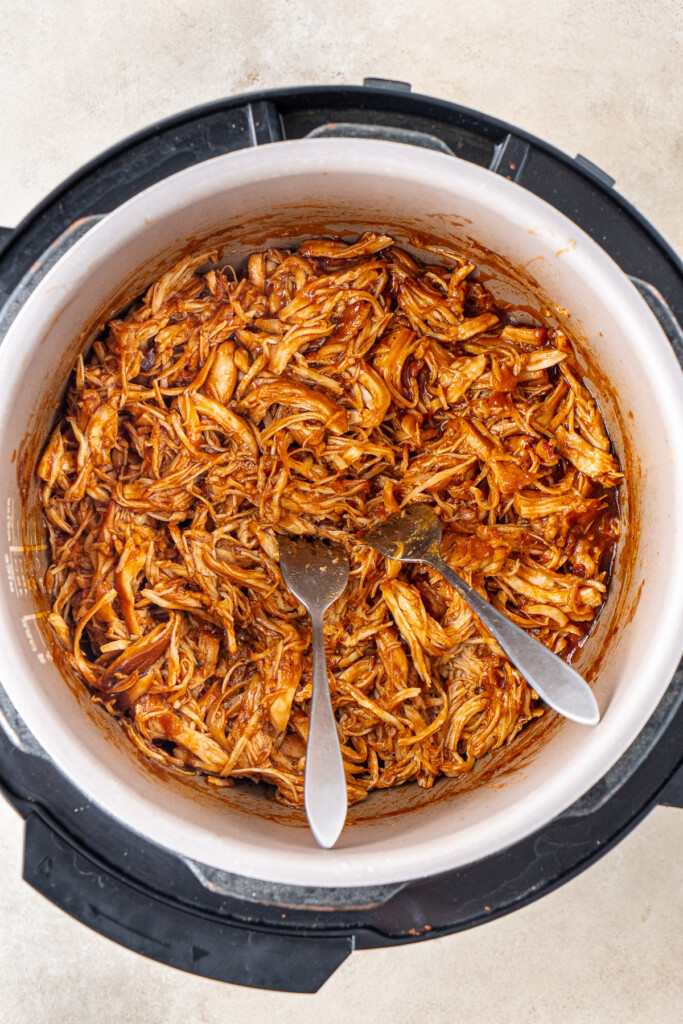 Shredding the chicken with forks in the slow cooker.