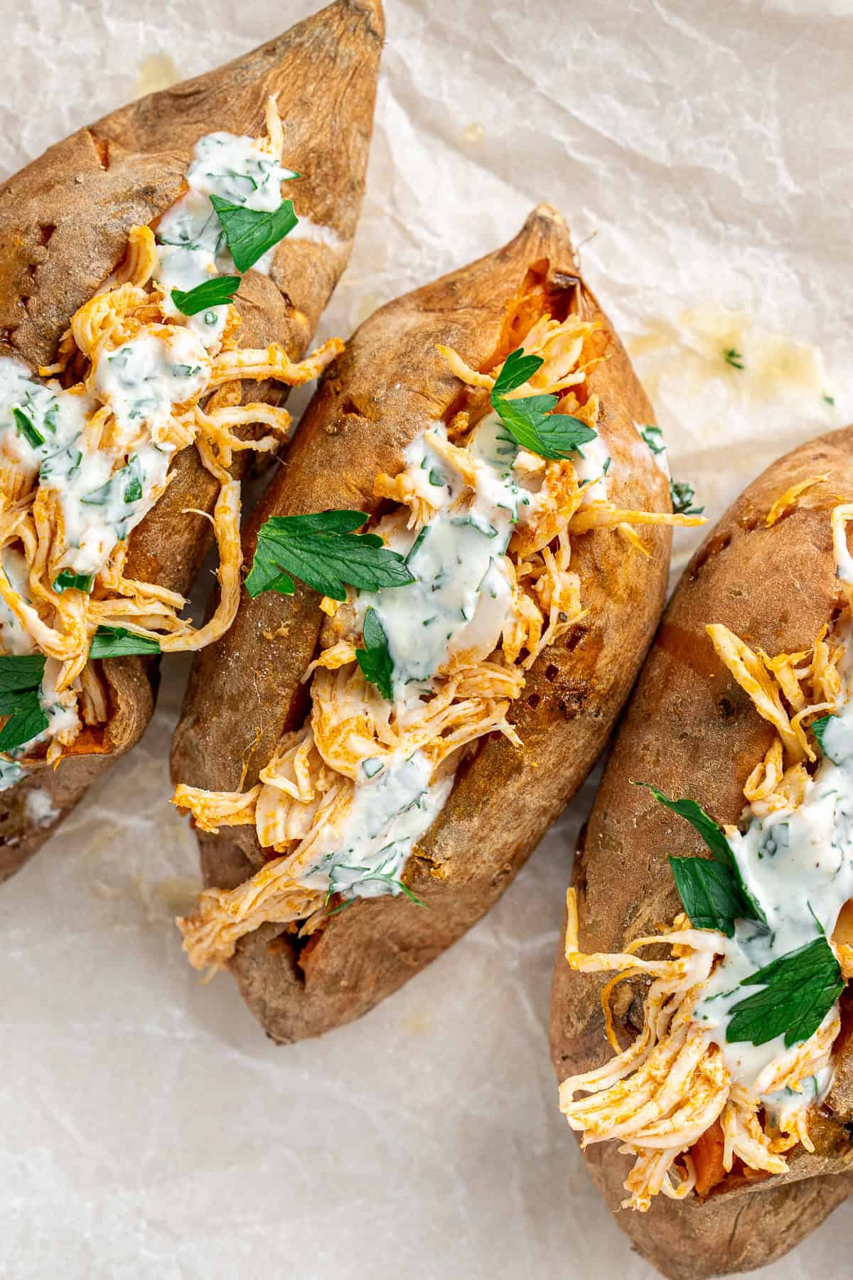 Close up of buffalo chicken stuffed sweet potatoes with ranch dressing.