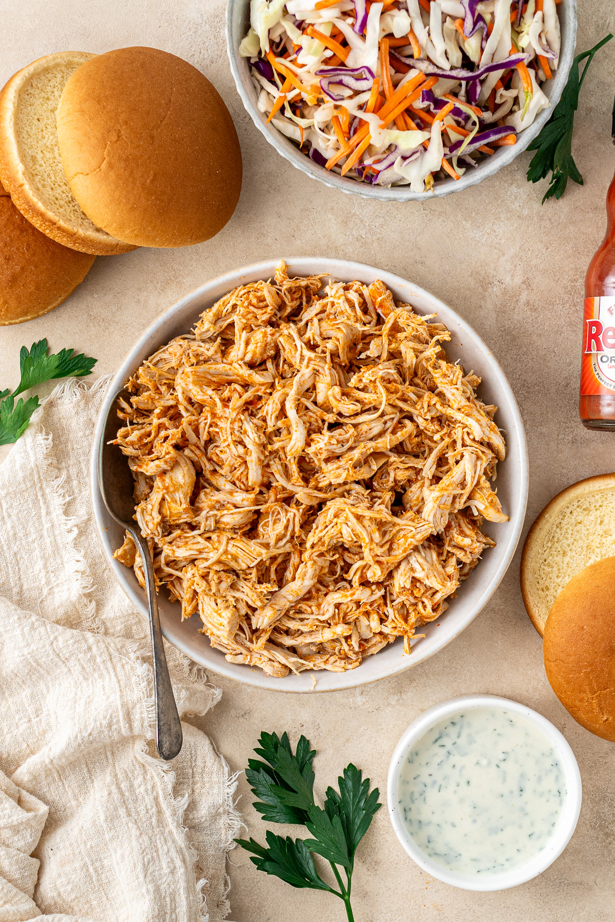 Shredded buffalo chicken in a bowl with a side of ranch.