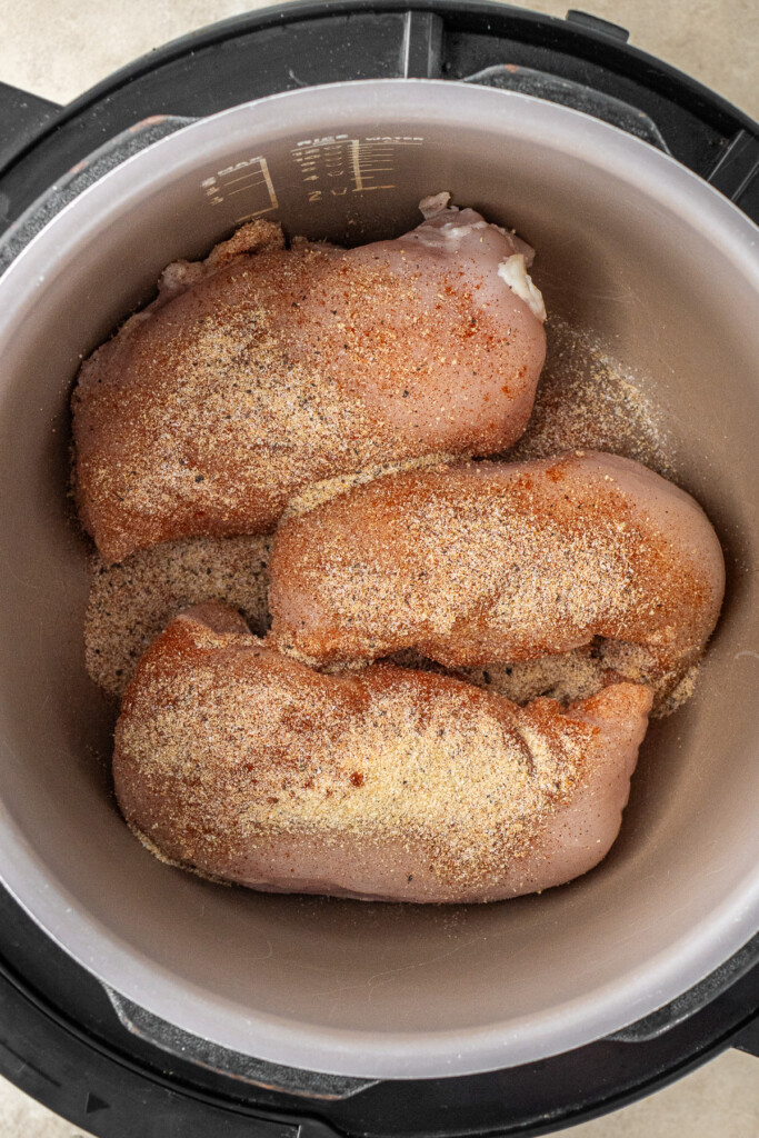 The chicken breasts in the slow cooker seasoned with spices. 