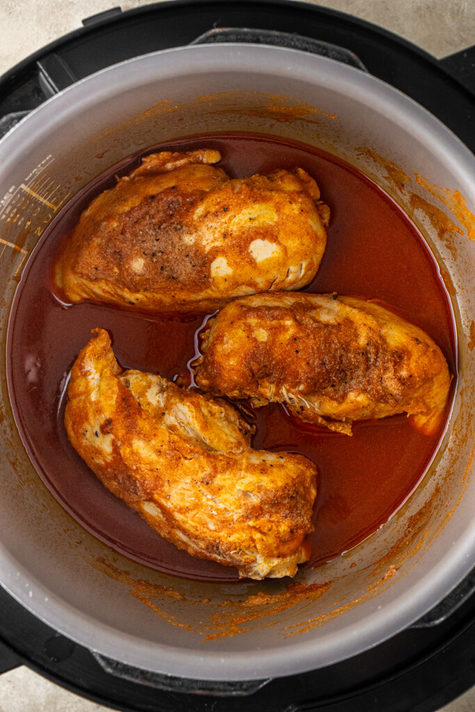 The cooked chicken breasts in the slow cooker.