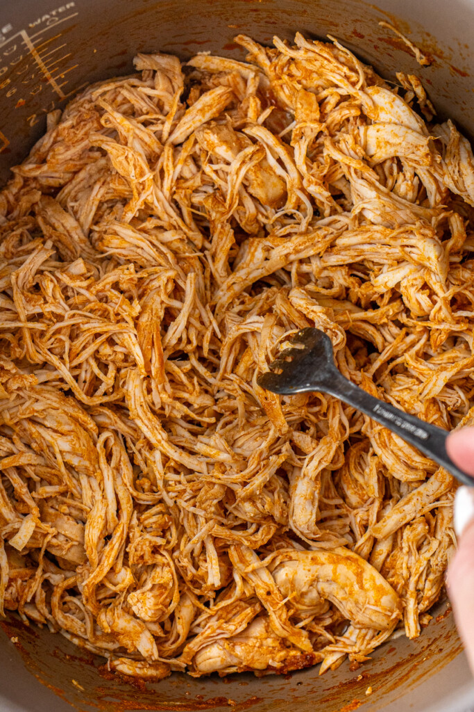 Shredding the chicken in the slow cooker with a fork.