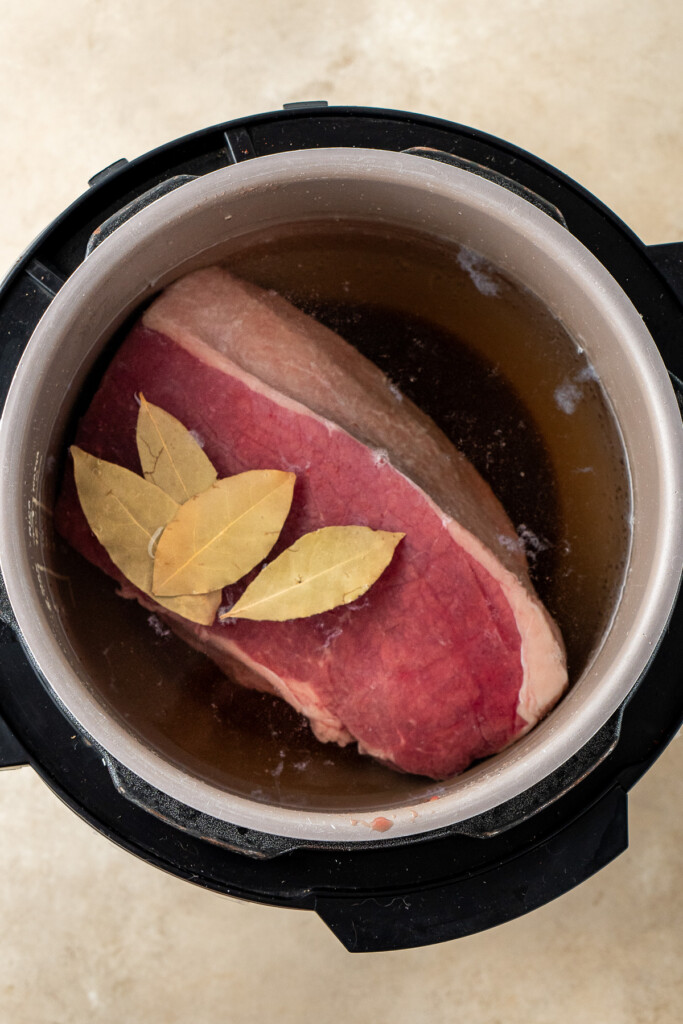 Raw corned beef in liquid in the slow cooker.