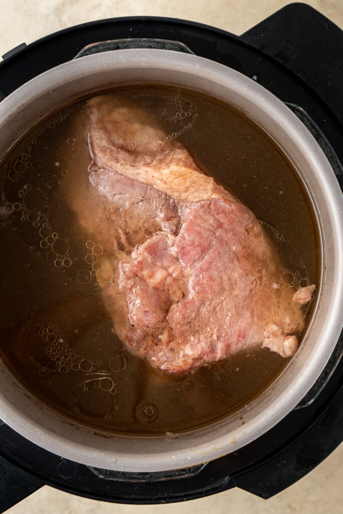 Cooked corned beef in liquid in the slow cooker.