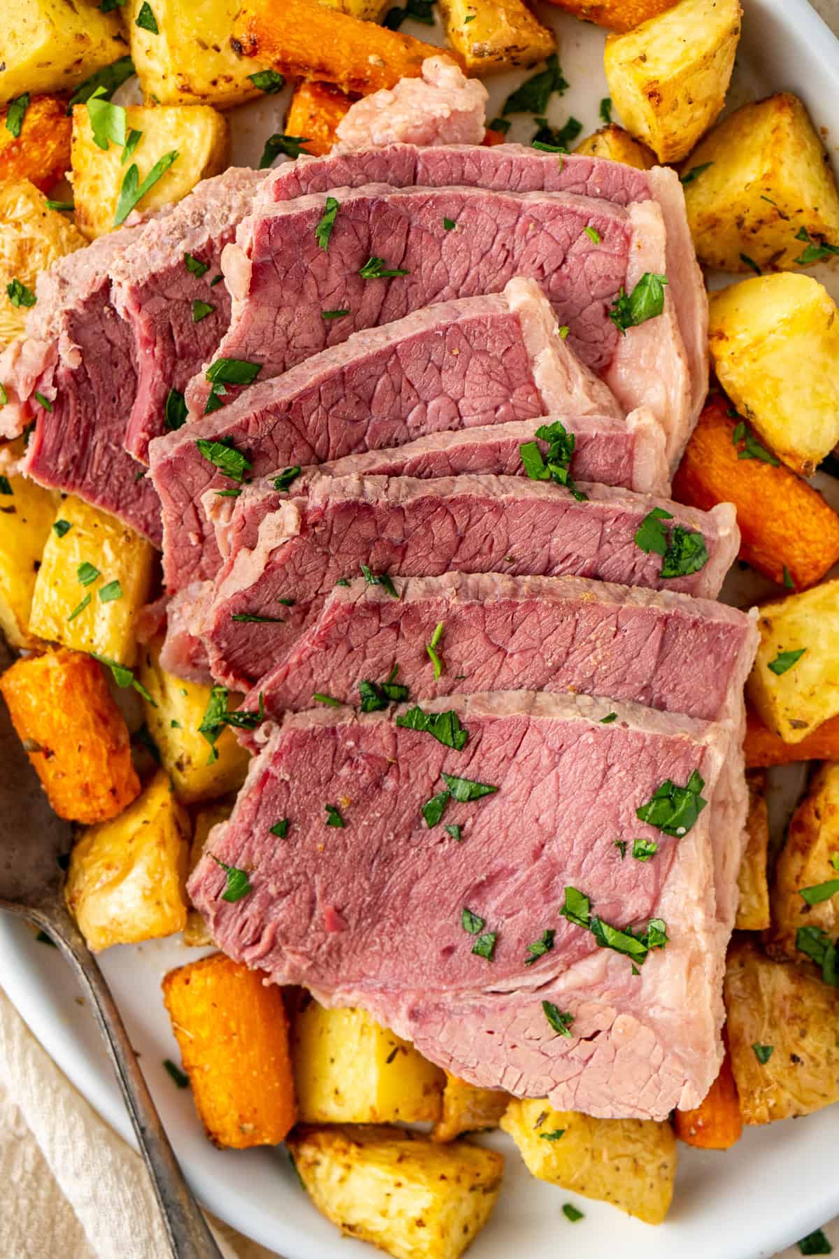 Close up of sliced corned beef with roast vegetables.