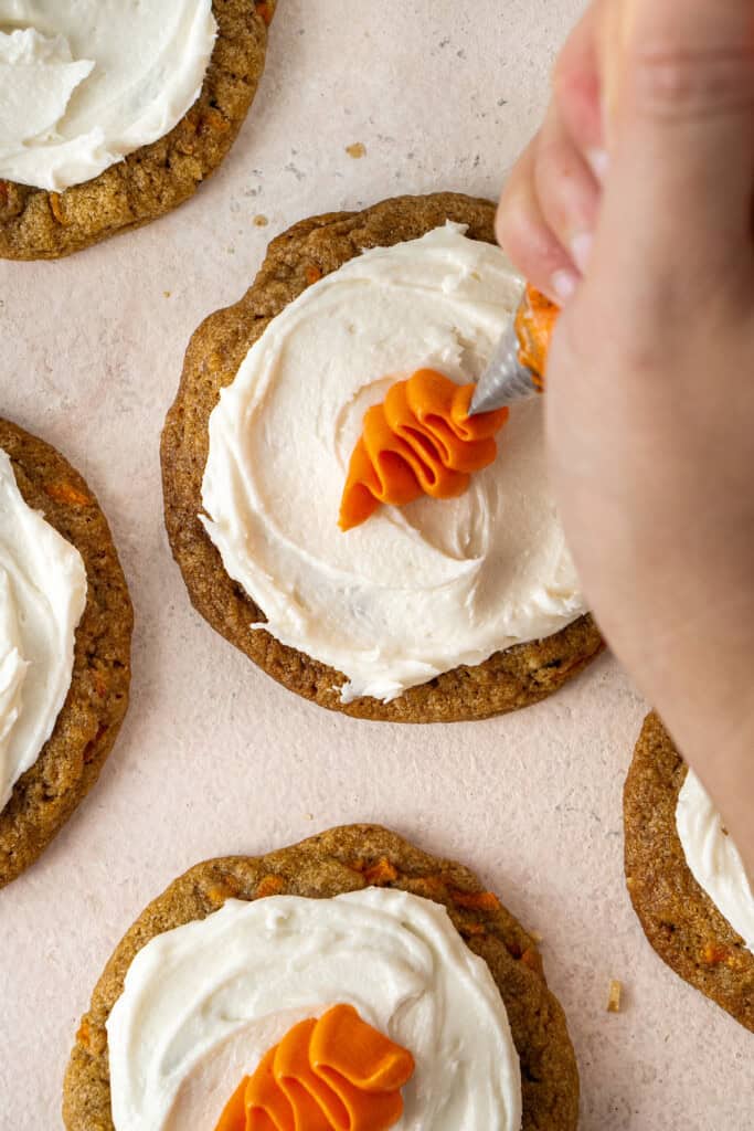 Piping the carrots on the frosted cookies.