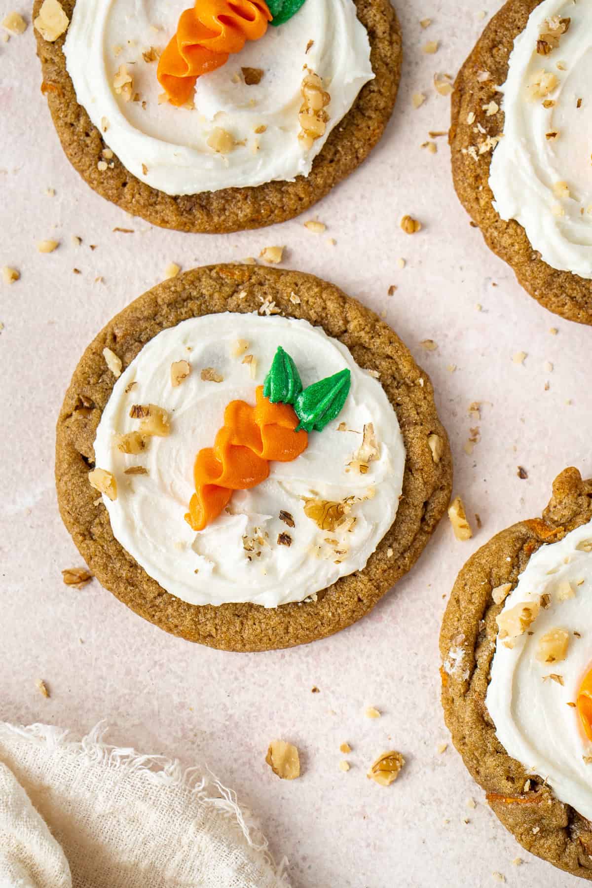 Frosted vegan carrot cake cookies decorated with piped carrots and chopped walnuts.