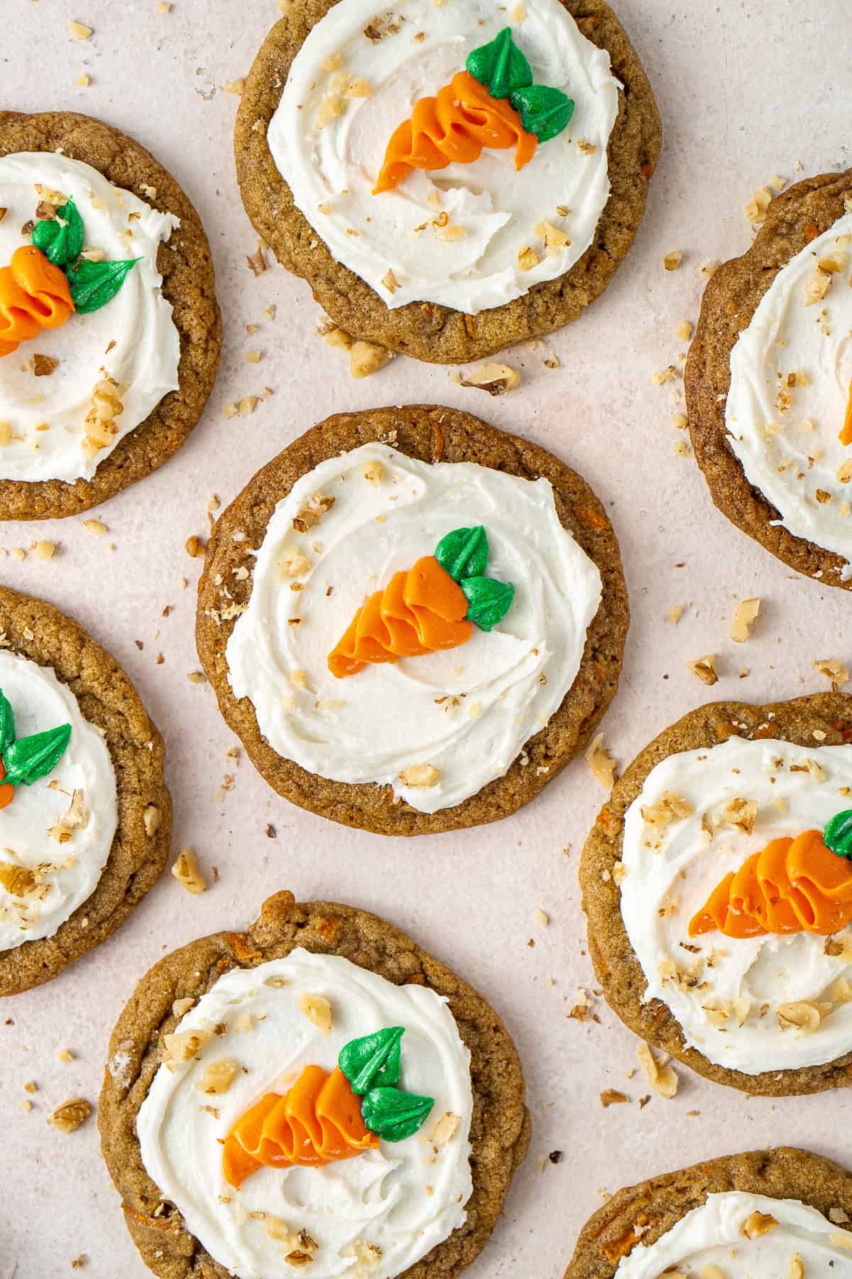 Frosted carrot cake cookies decorate with piped carrots laid out.