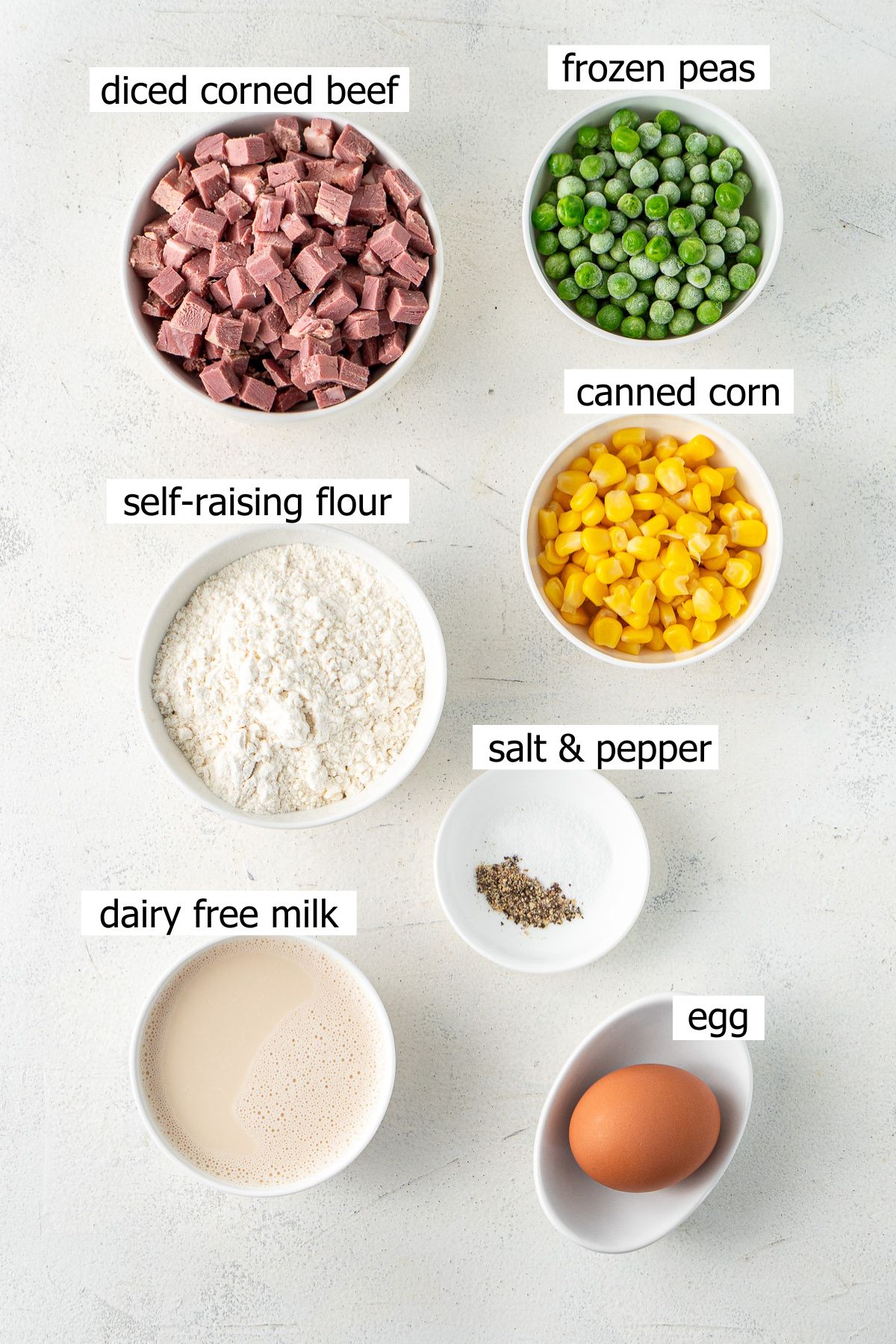 All ingredients needed to make corned beef fritters laid out in small bowls.