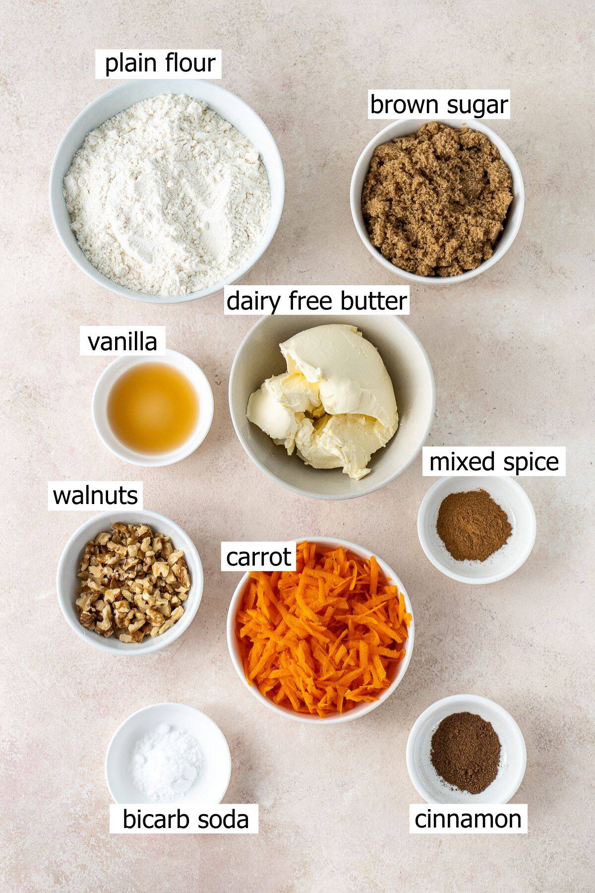 All ingredients needed to make vegan carrot cake cookies laid out in bowls.