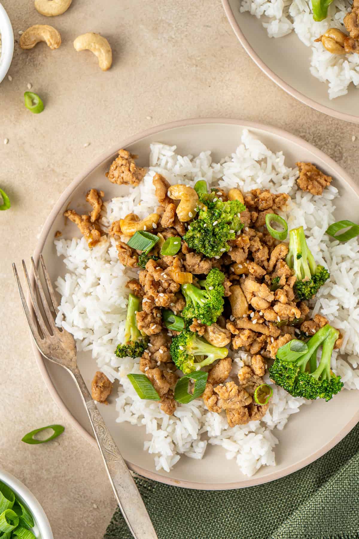 Close up of cashew chicken and broccoli with rice and a fork.