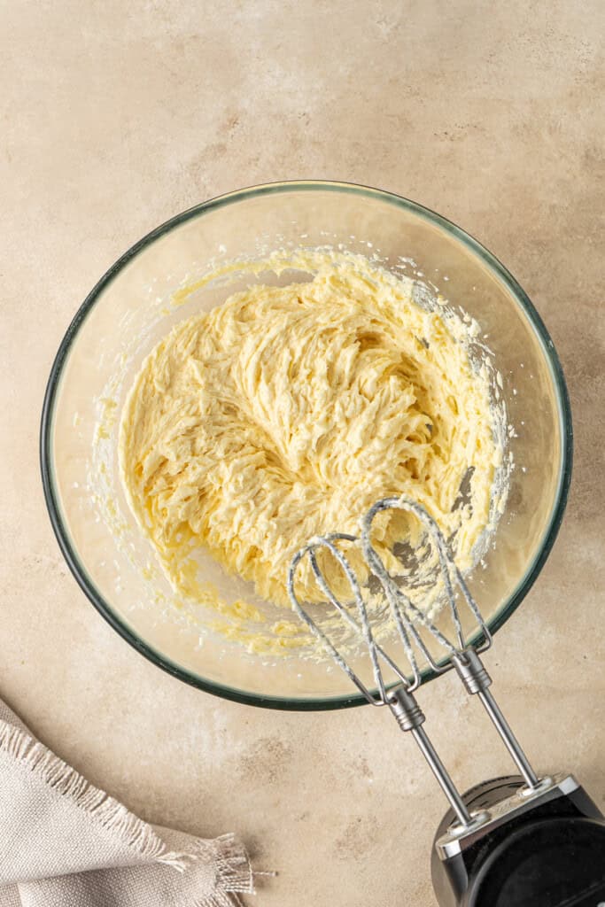 Beating together the butter, eggs, vanilla and sugar.