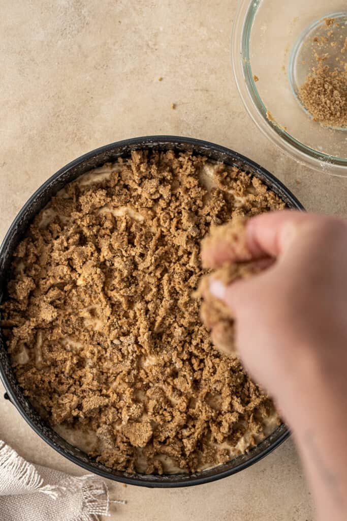 Adding the crumble topping to the cake.