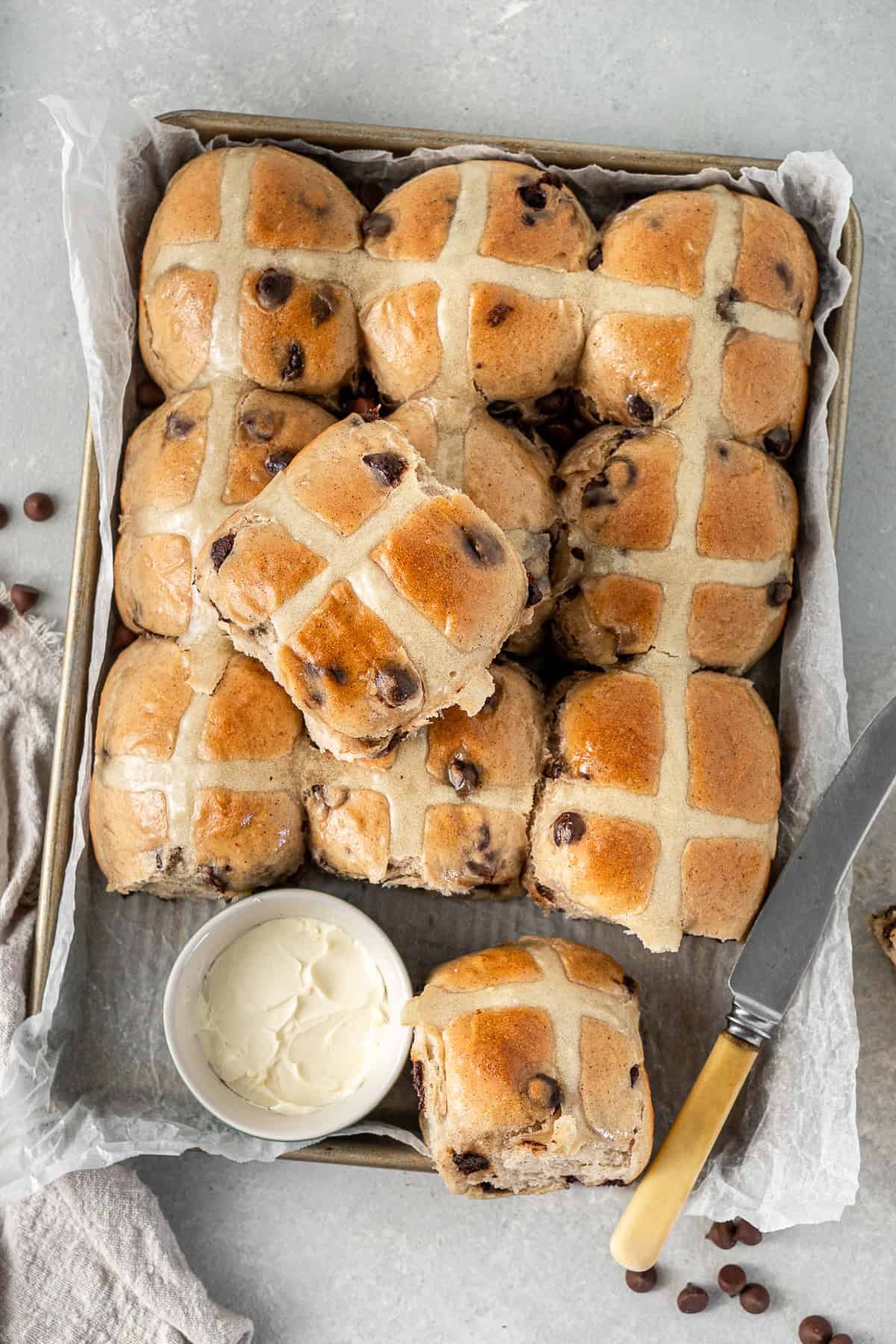 The choc chip hot cross buns on a tray with a knife and butter.