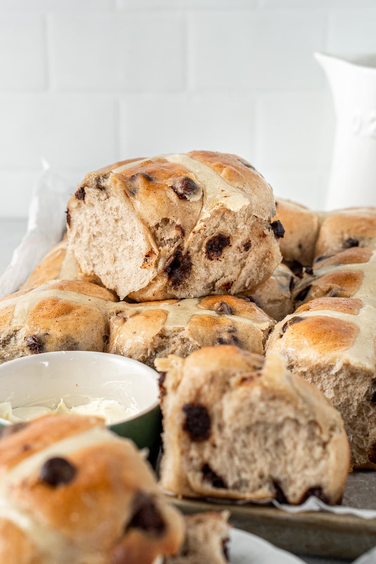 Choc chip hot cross buns stacked on top of each other.