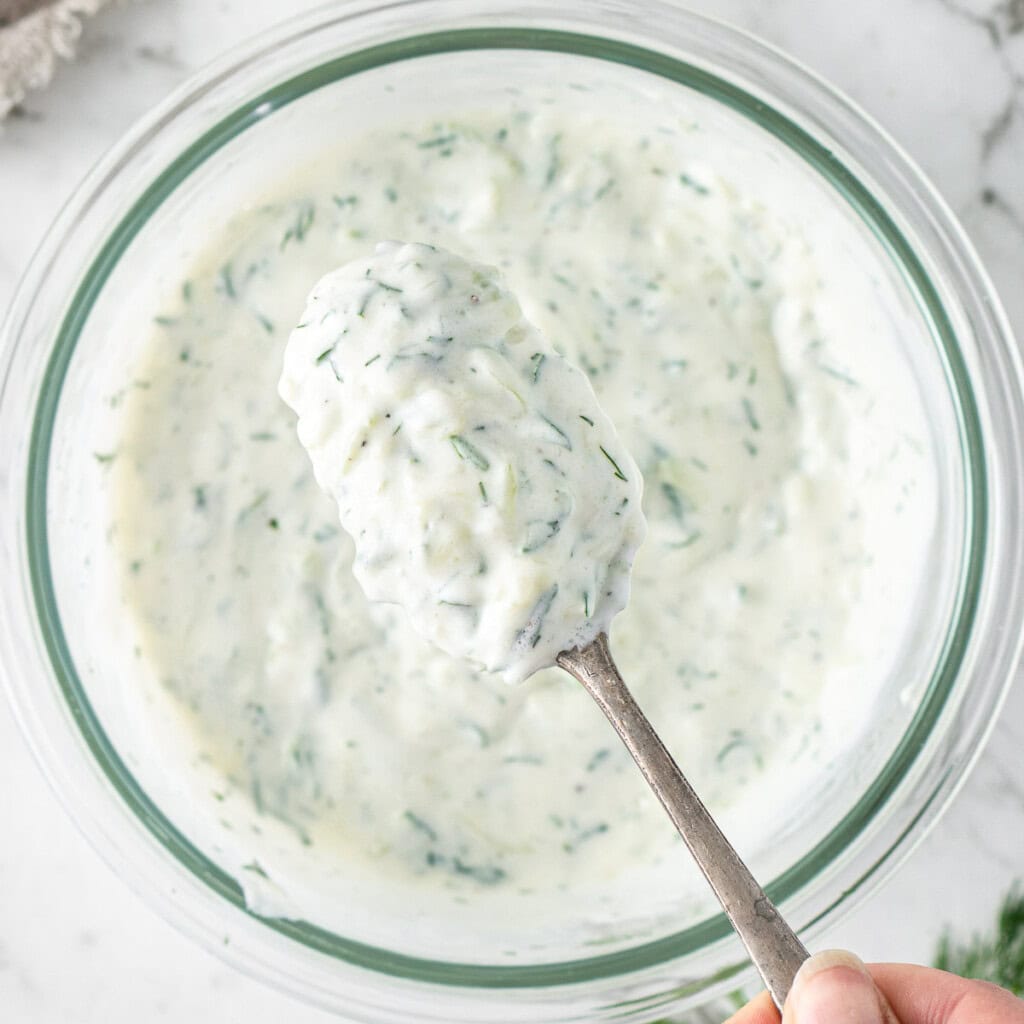 The dairy free tzatziki mixed up in a bowl with a spoon.