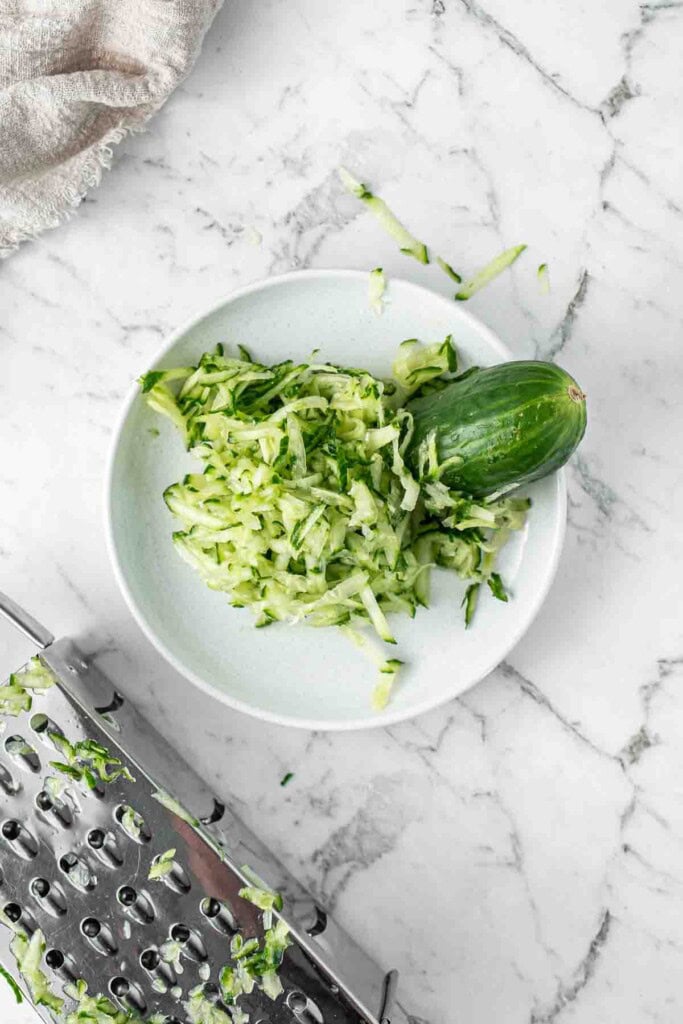Grating the cucumber using a box grater.